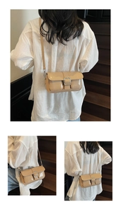 Detail view of khaki patent leather underarm bag with double pockets and silver buckles