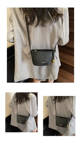 Détail du sac seau noir texture crocodile avec breloque cœur et logo doré