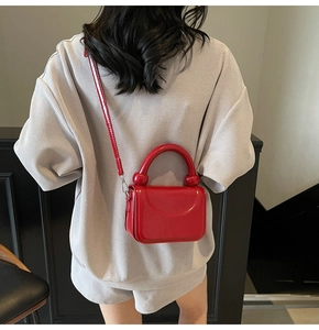 Détail du petit sac rouge en cuir ciré avec poignée rigide et bandoulière fine