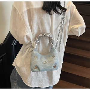 Detail view of denim texture handbag with silver butterfly charms and cloud-shaped handle