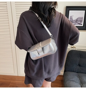 Close-up of a trendy silver metallic shoulder bag with a square buckle on a model