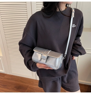 Detail of silver metallic crossbody bag featuring rectangular flap and large square buckle