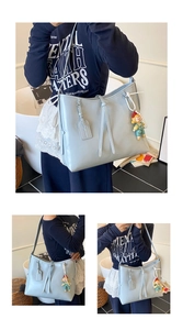 Detailed view of light blue soft leather tote bag with a cute doll charm and strap detail