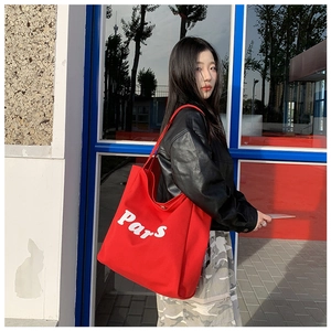 Detalle del bolso tote de lona roja con estampado blanco de París en una modelo de moda