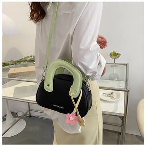 Détail d'un sac bandoulière aux couleurs contrastées avec poignée verte et fleurs
