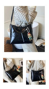 Detail of black glossy large tote bag with shoulder strap and cartoon doll charm