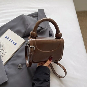 Détail du sac en cuir marron brillant avec poignée à bille unique et bandoulière amovible