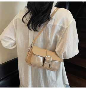 Detail of a chic beige underarm bag with a glossy finish and a silver square buckle