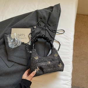 Detail of dark grey textured crossbody bag with silver butterfly charms and chain