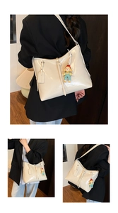 Detail view of cream white soft leather shoulder bag with cute doll charm and glossy finish