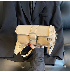 Detail of beige leather shoulder bag with a large silver square buckle and smooth texture