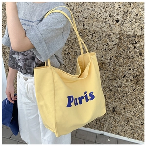 Detalle del bolso tote de lona amarilla con letras Paris en azul y correa de hombro