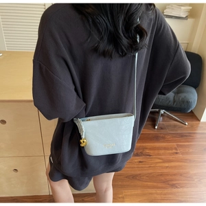 Détail du sac seau bleu clair à effet crocodile avec breloque lune dorée et logo en métal