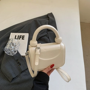 Détail du petit sac carré crème avec poignée ronde et boucle de réglage élégante