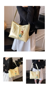 Detail of soft yellow faux leather tote bag with stylish cartoon clown pendant and logo tag