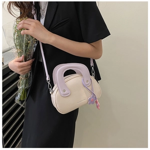 Détail du sac à main en cuir crème texturé avec anse violette et breloque fleurie