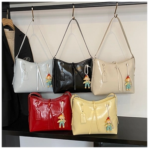 Detail view of glossy leather shoulder bags in five colors with cute cartoon pendants