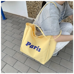 Detalle de bolso tote de lona amarillo claro con estampado Paris azul y correas anchas
