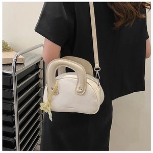 Détail du sac bandoulière crème avec texture grainée et breloque fleur jaune
