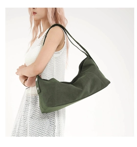 Close-up of a dark green canvas tote bag with metal rivets on a white dress model