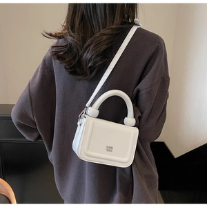 Détail du petit sac blanc avec poignée ornée de perles et logo en métal argenté