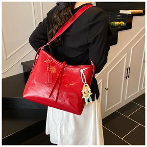 Chic red faux leather hobo bag featuring pearl doll charm and glossy texture detail