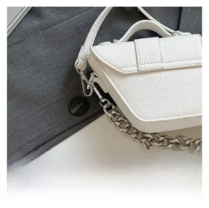Détail du cuir blanc grainé et de la bandoulière en chaîne argentée sur un sac à main chic