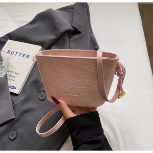 Détail du sac seau rose avec texture crocodile, lettrage doré et charme cœur