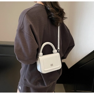 Vue détaillée du petit sac carré blanc avec poignée ronde porté par un mannequin