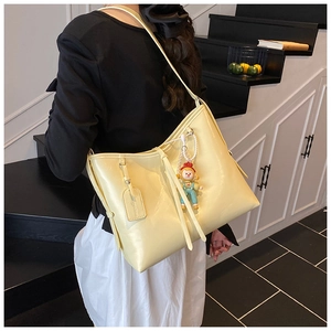Detail of soft cream yellow leather tote bag with cute cartoon doll and pearl chain detail
