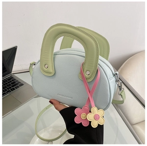 Gros plan du sac bandoulière bleu pastel avec poignée verte et breloque florale
