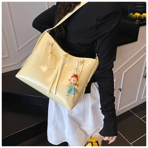 Detailed shot of yellow glossy leather tote bag with a pearl doll charm and long shoulder strap