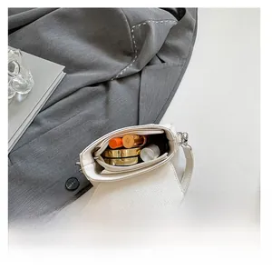 Vue intérieure du sac besace blanc montrant la capacité pour rouge à lèvres et poudrier