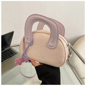 Détail du sac à main en cuir grainé avec poignée lavande et pendentif floral décoratif