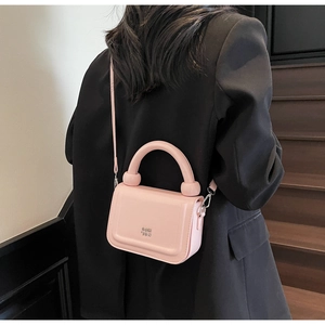 Gros plan du sac à main rose en cuir brillant montrant la texture et le logo en métal