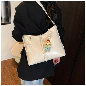Detail view of cream white glossy leather tote bag with cute cartoon doll charm