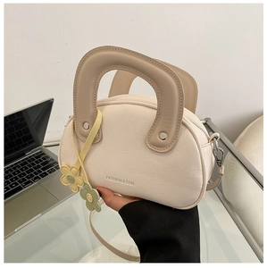 Détail du sac à main blanc crème motif litchi avec poignée marron et breloques de fleurs