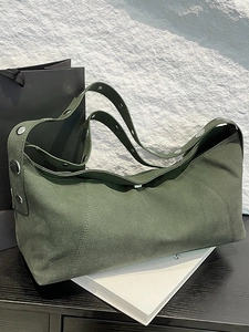 Minimalist dark green suede shoulder bag with silver metallic studs in a lifestyle setting