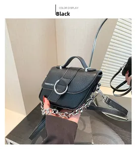 Détails d'un sac à main noir en cuir grainé avec boucle argentée et grosse chaîne