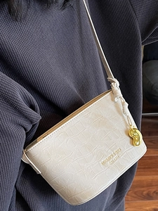 Sac seau blanc motif crocodile avec bandoulière nouée et pendentif doré en forme de rein