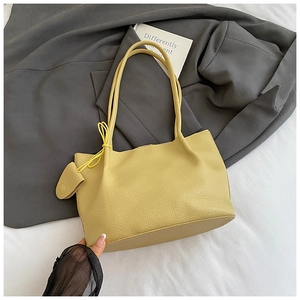 Detailed view of the yellow lychee grain tote bag with thin straps on a grey blazer