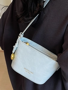 Sac seau bleu clair motif crocodile minimaliste avec fermeture éclair dorée sur tenue texturée