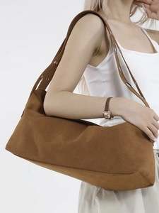 Brown suede tote bag with metal grommets on shoulder strap shown on model in studio