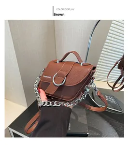 Détail du sac marron avec motif litchi, boucle argentée et bandoulière en chaîne