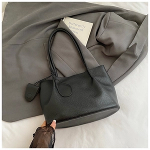 Detail of black pebbled leather tote bag with knot handle and matching charm accessory