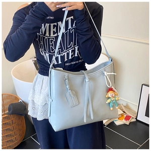 Detail of light blue PU leather tote bag with a cute doll pendant for casual use