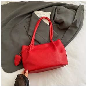 Detail of red pebbled leather tote bag with shoulder strap on grey blazer
