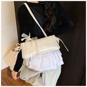 Détail d'un sac à bandoulière blanc crème brillant avec dentelle délicate et nœud élégant