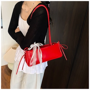 Vue détaillée du sac à bandoulière en cuir verni rouge avec nœud en dentelle blanche