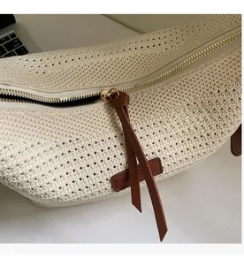 Detailed close-up of smooth metal zipper and leather patch on woven tote bag
